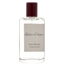 Perfume em frasco de vidro transparente retangular com tampa de plástico marrom escuro. Rótulo bege com o texto "Atelier Cologne" e "Bois Blonds Cologne Absolue" impresso em letras escuras.