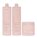 Três produtos da linha Glow Shine da marca Braé: um frasco de shampoo, um frasco de condicionador e um pote de máscara capilar, todos em tons de rosa claro com detalhes dourados.
