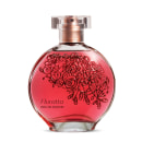 O frasco de vidro tem um formato arredondado e é feito de vidro transparente, com um bocal de metal rosado. O líquido dentro do frasco tem uma cor vermelha vibrante. Na parte frontal do frasco, há um desenho decorativo de rosas vermelhas estilizadas.