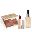 paleta de sombras em tons terrosos e rosados em uma embalagem dourada. Batom vermelho vibrante. Frasco de primer líquido com partículas de ouro. As embalagens exibem o logotipo Eudora Glam Metals em letras pretas sob fundo dourado e prateado.