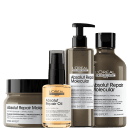 A imagem mostra produtos da marca L'Oréal Professionnel. Há 4 itens: um frasco de shampoo marrom de 300ml, um frasco de leave-in marrom de 250ml, um frasco de máscara capilar de 250ml com tampa preta, um frasco de óleo capilar dourado de 30ml.