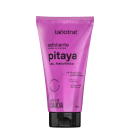 O produto exibido é um esfoliante corporal da marca Labotrat, com o nome "pitaya" e a indicação de conter ácido hialurônico. A embalagem é um tubo de plástico rígido de cor rosa vibrante, com o nome da marca e do produto claramente visíveis.