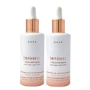 Dois frascos de tônico antiqueda para cabelos da linha Defense marca Braé. A embalagem branca exibe o nome do produto "DEFENSE Tônico Antiqueda" e a descrição "Anti Hair Loss Tonic" em inglês. Também menciona que fortalece os fios e combate a queda.
