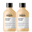 São dois frascos de shampoo profissional da linha Absolut Repair da L'Oréal Professionnel. Os frascos têm formato cilíndrico com tampa preta brilhante. O corpo dos frascos é bege claro e apresenta o logotipo "L'Oréal Professionnel Paris" em letras pretas.