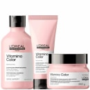 Três produtos de cuidados capilares da linha Vitamino Color da L'Oréal Professionnel. Um é um shampoo profissional, o outro é um condicionador profissional e o último é uma máscara de tratamento capilar. Todos possuem embalagem rosa, com detalhes pretos.