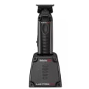 A imagem mostra a máquina de acabamento na base carregadora. O produto tem um design preto. O corpo principal é retangular com uma empunhadura ergonômica. Na parte superior, há uma lâmina de corte com pentes ajustáveis.