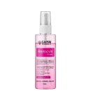 A imagem mostra um frasco plástico transparente com um líquido rosa claro dentro. O frasco tem um borrifador branco na parte superior. É um demaquilante bifásico de 150ml para remover maquiagem com facilidade, indicado para rosto, lábios e olhos.
