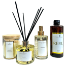 Linha de produtos da marca Perfuma & Decora. Inclui um difusor de aromas em frasco de vidro âmbar com rótulo "REFIL", um frasco de home spray transparente, um difusor de aromas em frasco de vidro com conjunto de varetas pretas e uma vela perfumada.