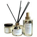 Linha de produtos da marca Perfuma & Decora. Há um difusor de aromas em um frasco de vidro transparente e varetas pretas, uma vela perfumada em um pote de vidro transparente com uma tampa preta, e um spray para ambiente em um frasco de vidro transparente.