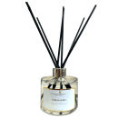 Difusor de aromas em frasco de vidro transparente. Contém hastes pretas que saem do bocal para difundir o aroma. Rótulo na parte frontal com o texto "Perfuma & Decora", "Magnolia Pacifica" e "Super Premium".