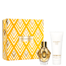 Conjunto de produtos de beleza da marca Rabanne, incluindo um frasco de perfume dourado com detalhes em relevo e uma caixa com padrão geométrico em tons de amarelo, acompanhado de um tubo de loção corporal.
