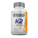 Suplemento alimentar em cápsulas contendo a vitamina K2 com dosagem de 65 mcg por cápsula. A embalagem é um frasco plástico branco com tampa rosqueável cinza, exibindo o nome do produto e informações sobre a composição e modo de uso.