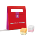 Caixa vermelha com texto "Quem Disse, Berenice?" e dois produtos de beleza em formato cúbico, um amarelo e outro rosa, com o mesmo texto impresso.