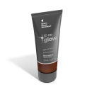 O produto apresentado é uma base líquida da marca Tô no Glow, com embalagem em tubo plástico de cor cinza escura. O rótulo exibe o nome da marca e o texto "Radiância natural, leveza e conforto" em letras brancas.