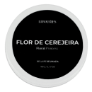 Vela perfumada LIBOUGIES, com o nome "FLOR DE CEREJEIRA" impresso em letras brancas sobre um fundo preto. A embalagem é circular, com um anel branco ao redor. A vela possui 90g.