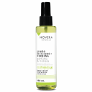 A imagem mostra o body splash Novera Naturals com fragrância de limão siciliano e verbena. O frasco é de 150ml, transparente, permitindo ver o líquido verde claro dentro. Há também logos indicando que é vegano, natural e não testado em animais.
