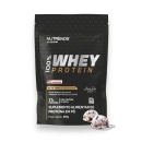 Suplemento alimentar da marca Nutrends. A embalagem é um pacote preto com o logotipo da marca e a informação de que se trata de 100% whey protein, com 21g de proteína por porção.