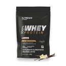 Suplemento alimentar de proteína em pó da marca Nutrends. A embalagem é um pacote preto com o logotipo da marca e a informação "100% Whey Protein" em destaque. O pacote contém 907g