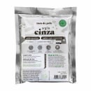 Argila cinza da marca Tom de Pele, em uma embalagem plástica de 100g. A embalagem possui informações sobre as propriedades da argila, indicando que é um produto 100% natural, vegano, sem crueldade animal e adequado para peles com acne e manchas.