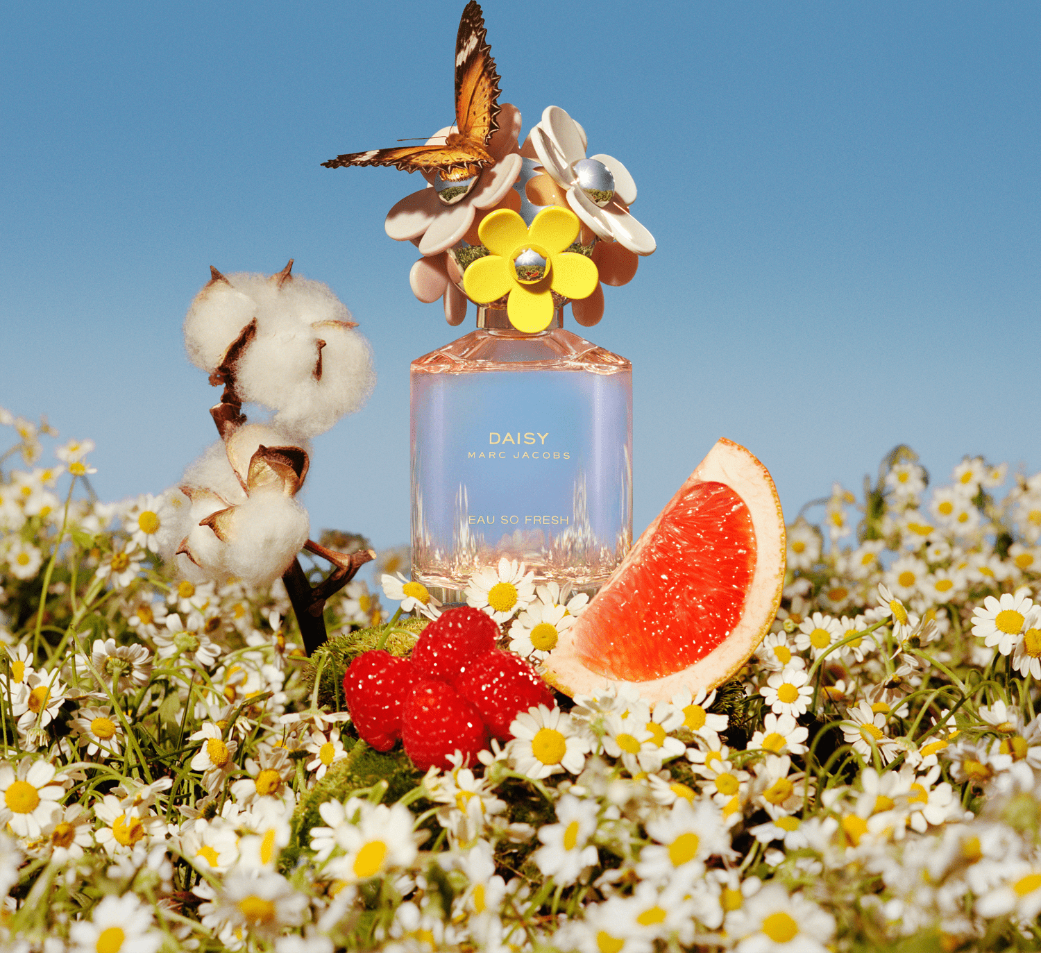 Frasco de perfume rosa da linha Daisy Marc Jacobs, com tampa decorada com flores amarelas e brancas. Rótulo com o nome da fragrância "Daisy Marc Jacobs Eau So Fresh" em letras douradas.