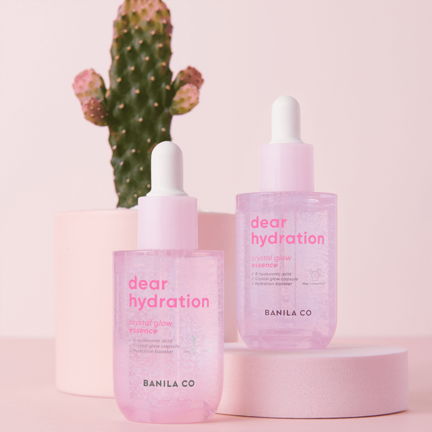 Duas embalagens do produto em um cenário rosa claro com um cacto compondo a fotografia na parte de trás.
