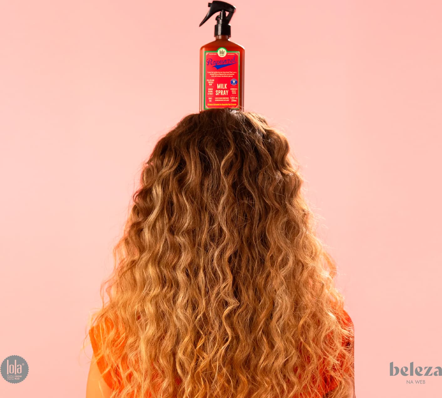 Frasco de spray de leite da marca Lola From Rio, com rótulo rosa e verde destacando a fórmula natural e vegana do produto. O frasco possui um gatilho preto e contém 250 ml do produto.