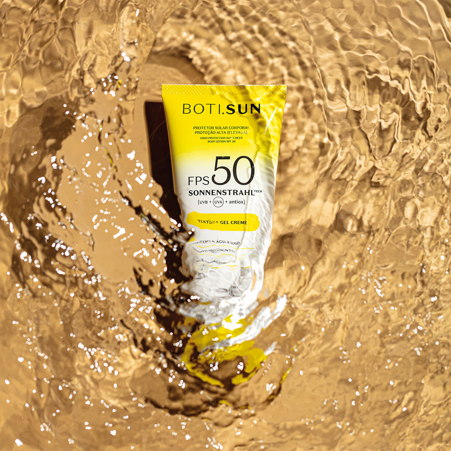 Bisnaga amarela e branca com tampa amarela e letras pretas de protetor solar corporal FPS 50 da marca Boti.Sun em um cenário d areia de praia molhada.