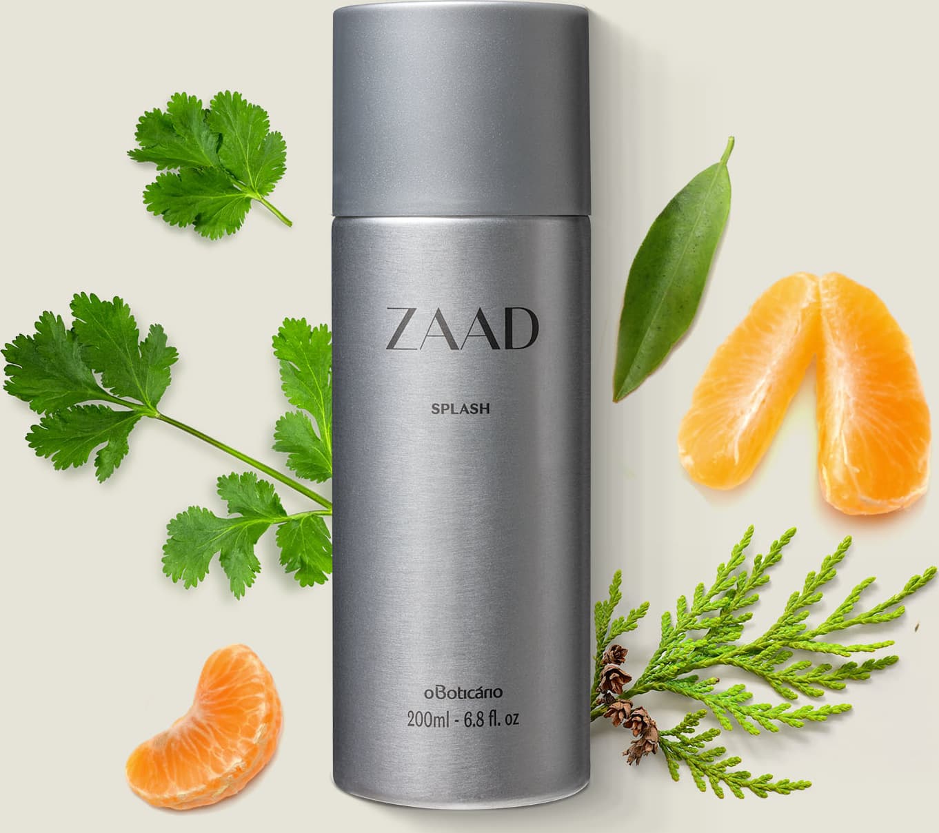 Frasco cilíndrico prateado com tampa e letras cinzas de body splash Zaad rodeada por folhas verdes, fatias de laranja e galhos com folhagem, sobre superfície clara.