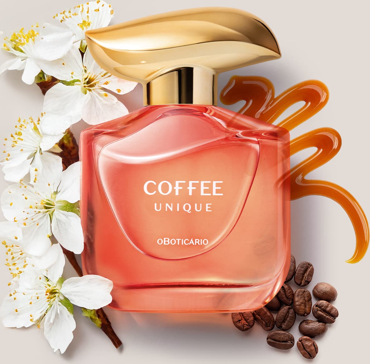 Imagem de um frasco rosa contendo 100ml de desodorante colônia da marca Coffee Woman Unique, com tampa dourada, em meio a flores brancas e grãos de café e um rastro de caramelo sobre superfície clara.
