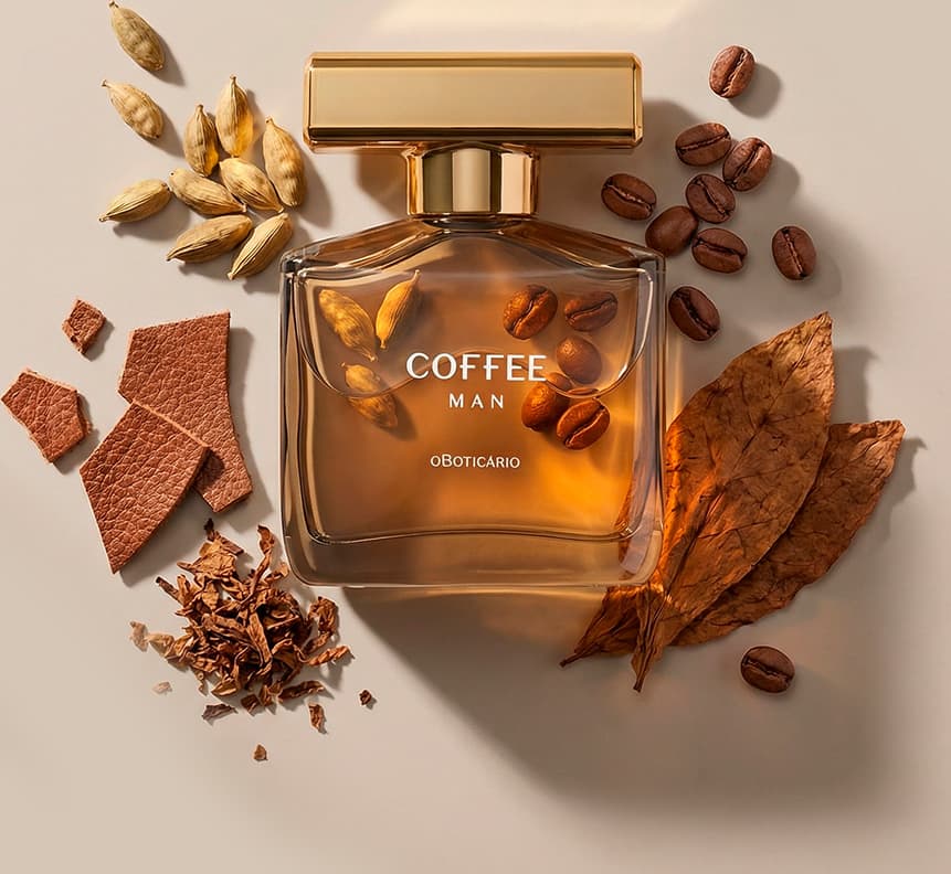 Imagem do vidro marrom do desodorante colônia da marca Coffee Man sobre superfície bege, rodeado por grãos de café, folhas secas, pedaços de madeira e outros elementos que sugerem um ambiente aconchegando e de muita sofisticação.