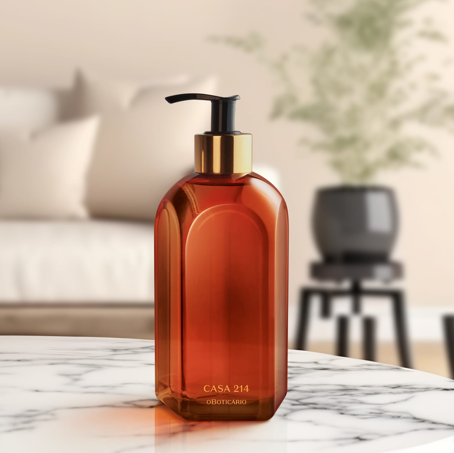 Vidro laranja de tampa dosadora preta com detalhe e letras douradas de sabonete líquido Casa 214 Vanilla Sublime sobre superfície de mármore, com objetos escuros desfocados ao fundo, em ambiente iluminado e minimalista.
