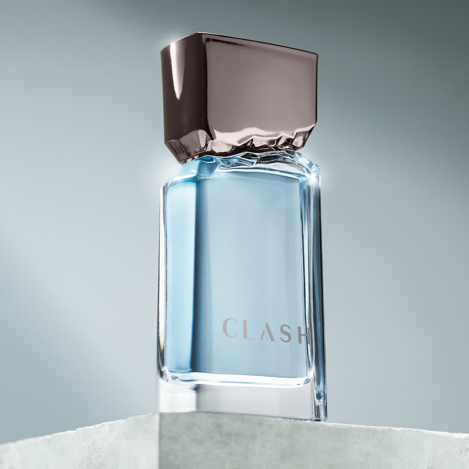 Frasco de item de perfumaria da marca Clash sobre superfície de mármore branco, com fundo desfocado em tons de azul e cinza.
