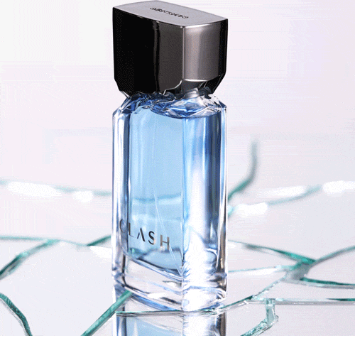 Vídeo mostra frasco de item de perfumaria da marca Clash fazendo um giro de 360 graus sobre superfície de vidro craquelada, com reflexos e iluminação azulada, em ambiente minimalista e claro.