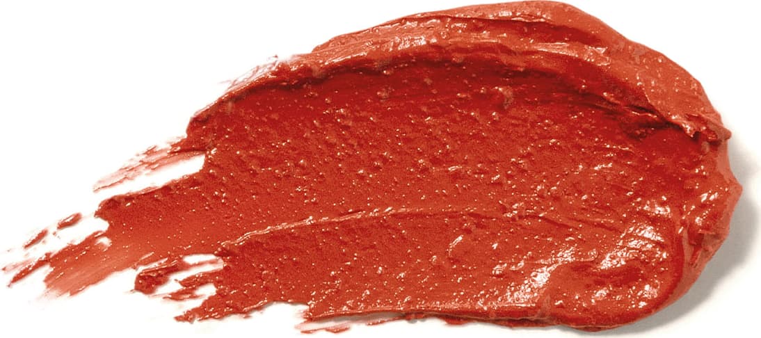 Textura cremosa e brilhante do batom glossy na cor Coral da marca Make B. A aparência é brilhante e leve e está espalhada em superfície branca.