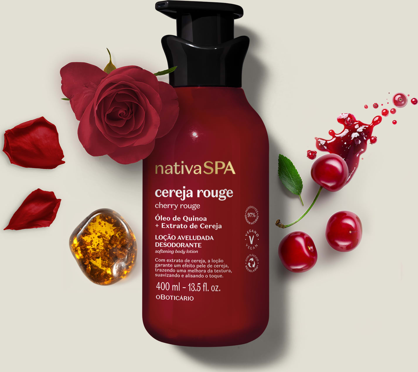 Embalagem vermelha escura de loção aveludada corporal Nativa SPA Cereja Rouge cercada por pétalas de rosa vermelha, cerejas e respingos de líquido vermelho sobre superfície clara.