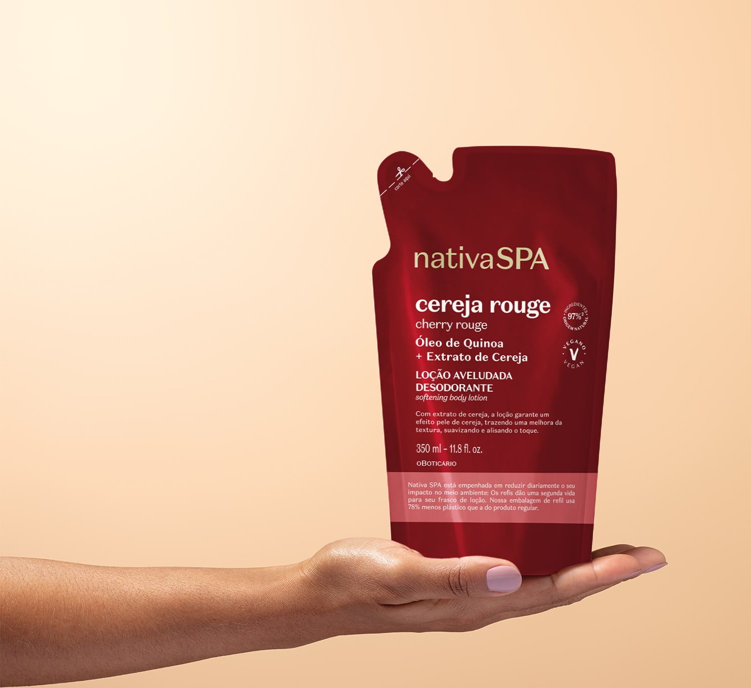 Mão feminina com unhas pintadas segurando um refil de loção aveludada corporal da marca Nativa SPA Cereja Rouge em sachê vermelho escuro, letra brancas e detalhe rosa em fundo rosa claro.