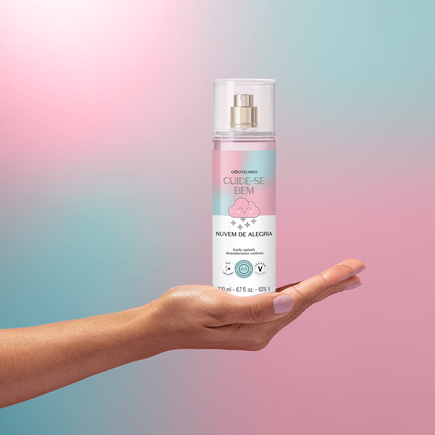 Embalagem de body splash Cuide-se Bem Nuvem de Alegria em formato de spray sobre fundo degradê rosa e azul, com nuvem estilizada sendo segurado por mão feminina.