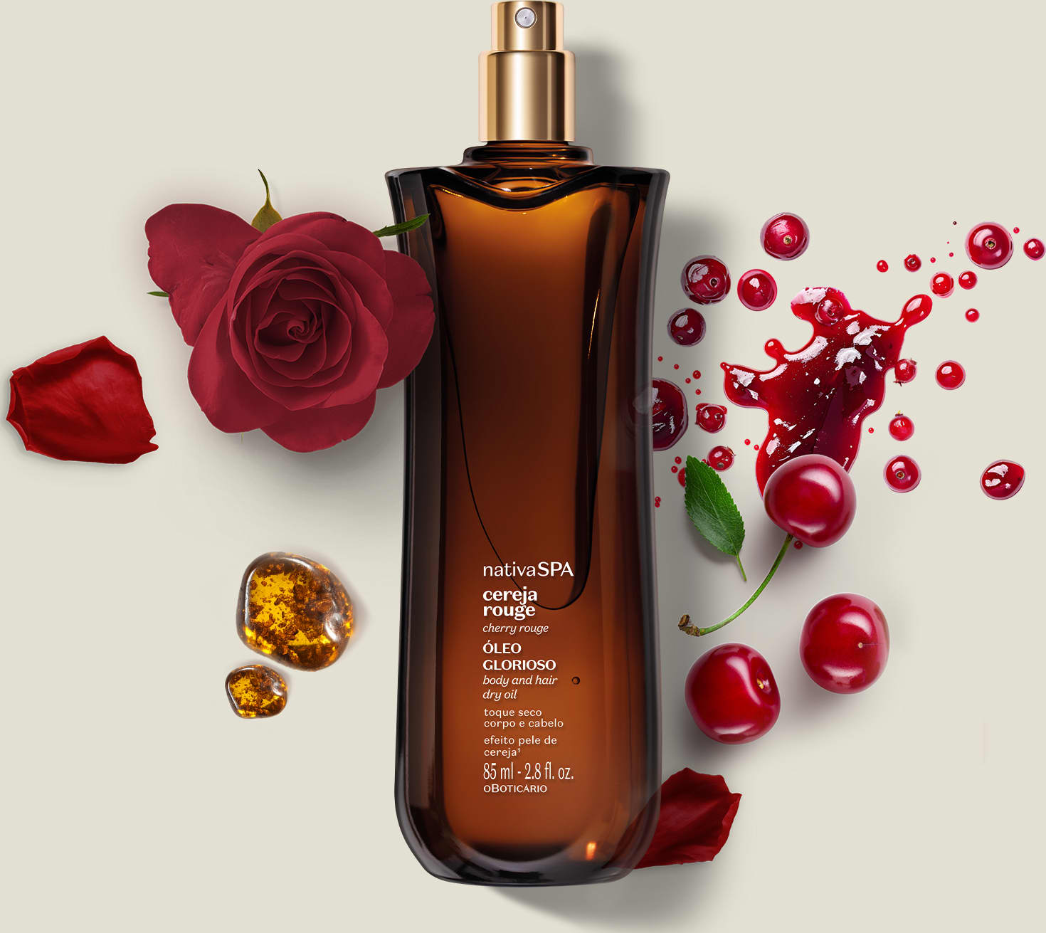 Frasco de vidro vermelho com tampa dourada. Rótulo indica "nativa SPA cereja rouge óleo glorioso ". Acompanhado por rosas vermelhas, cerejas, folhas e pedras âmbar. Embalagem de 85ml. Cores predominantes são vermelho, dourado e âmbar.
