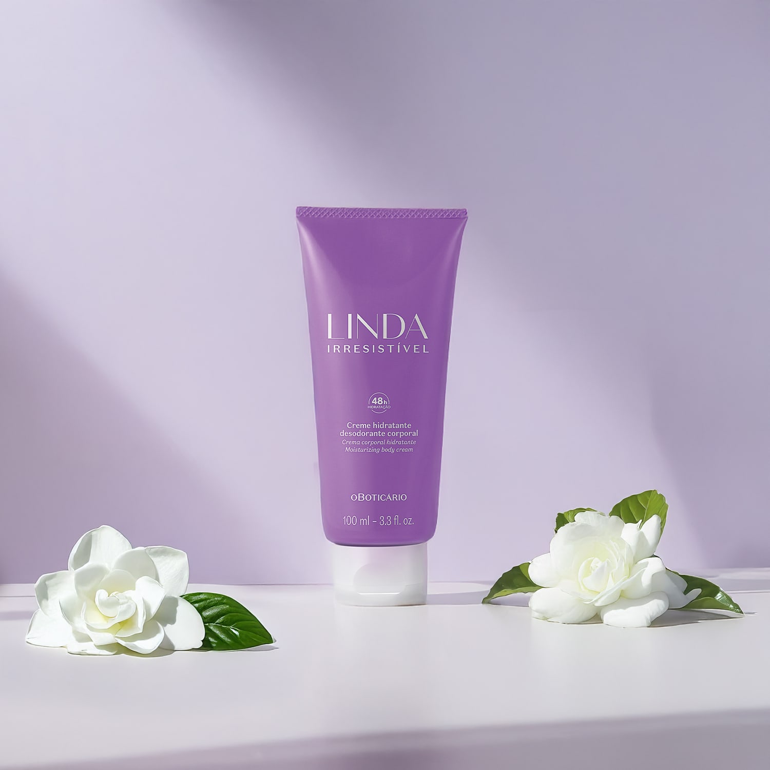 Tubo de creme hidratante corporal da marca Linda Irresistível em embalagem roxa, sobre superfície branca com flores brancas ao redor, em ambiente com fundo roxo claro.