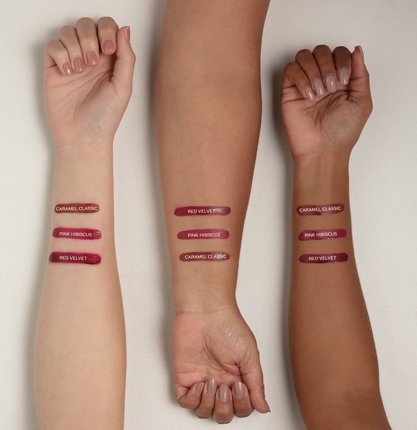 Imagem mostra três braços de cores diferentes estendidos sobre superfície branca sendo o braço mais a direita de pele negra, o do meio de pele parda e o da esquerda com pele branca, todos com diversos tons de batom aplicados sobre eles e seus códigos.
