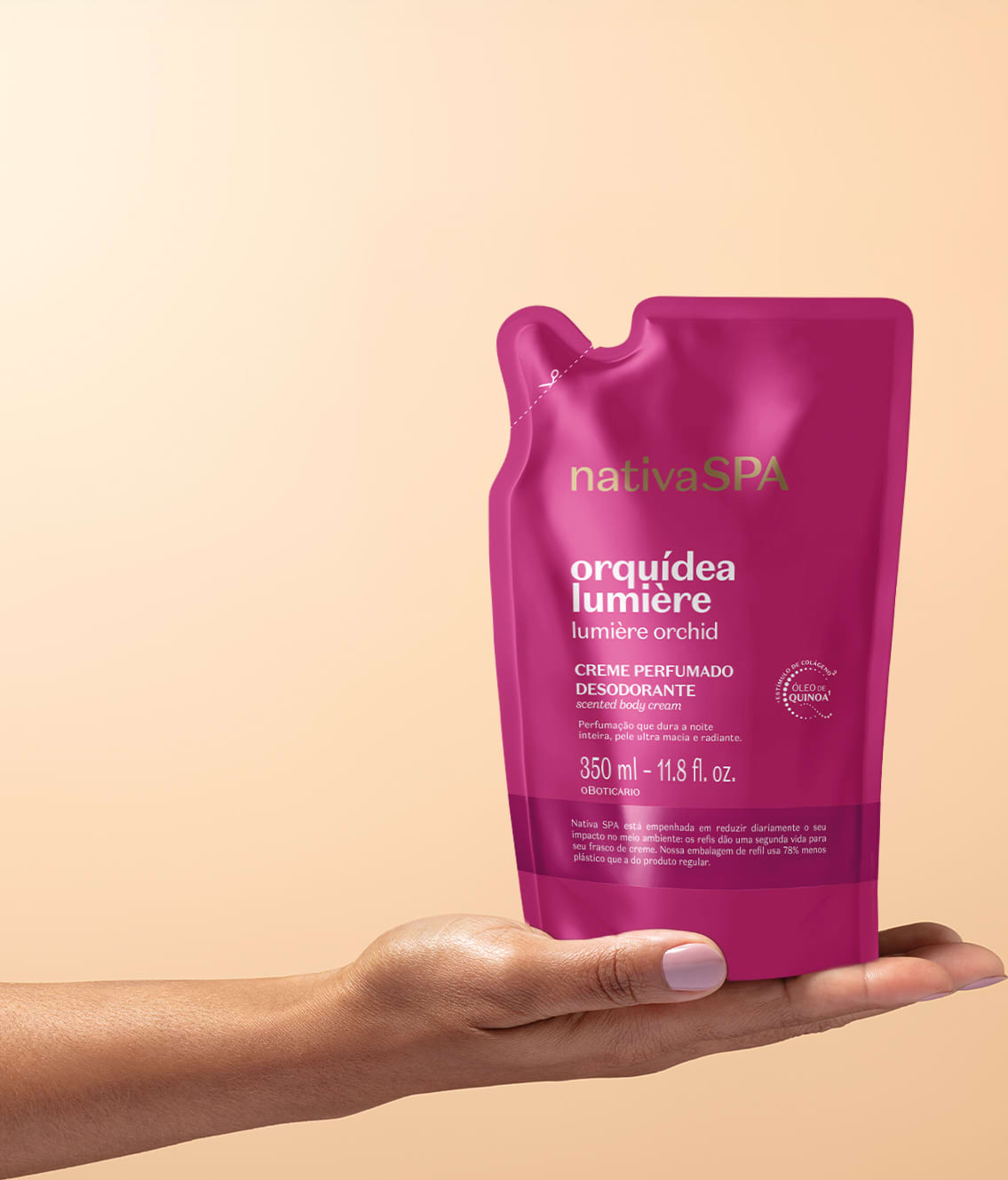 Embalagem flexível contendo refil de creme perfumado desodorante da marca Nativa SPA Orquídea Lumière, na cor rosa vibrante posicionada sobre uma mão feminina espalmada em fundo na cor salmão.