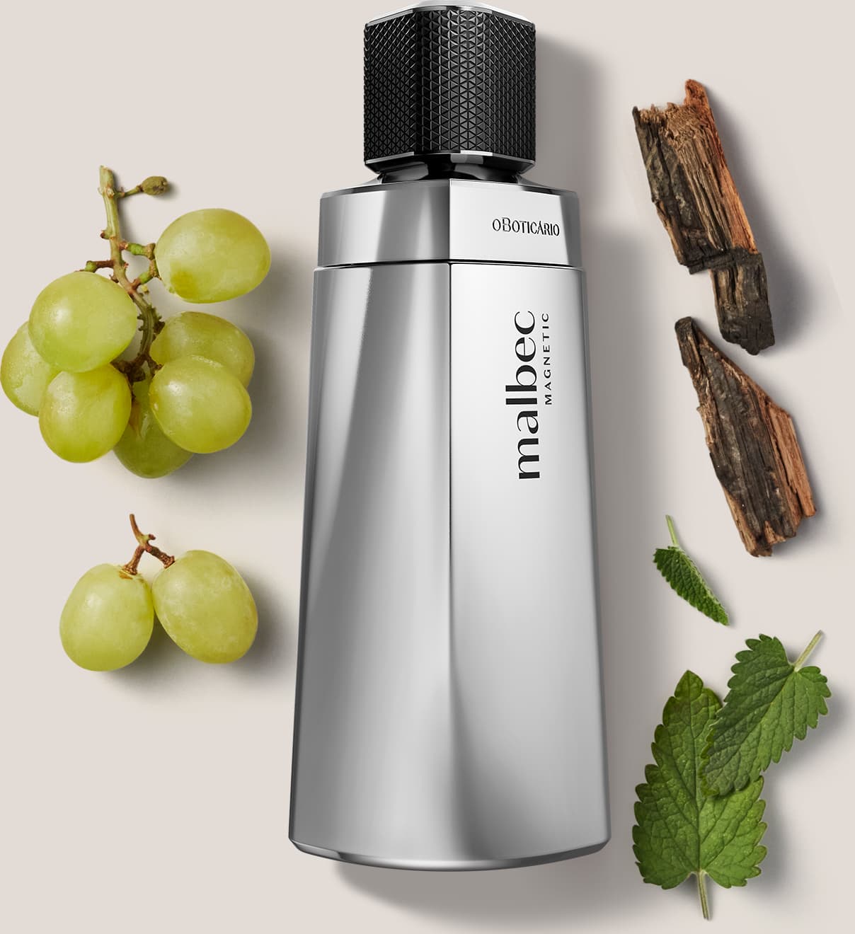 Frasco de item de perfumaria prateado com design geométrico e tampa preta. Ao redor do frasco, há alguns elementos naturais, como uvas verdes, lascas de madeira e folhas, que sugerem uma fragrância amadeirada-frutada para o produto.