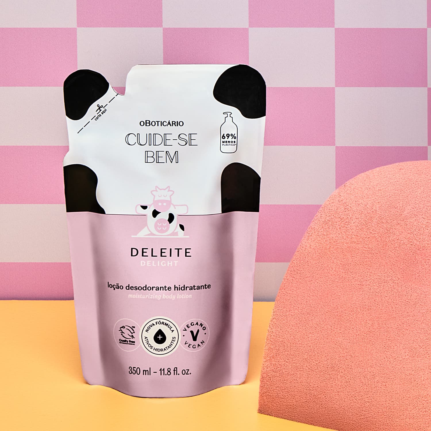 Embalagem refil de loção hidratante corporal Cuide-se bem Deleite em fundo rosa e amarelo, com esponja laranja ao lado.