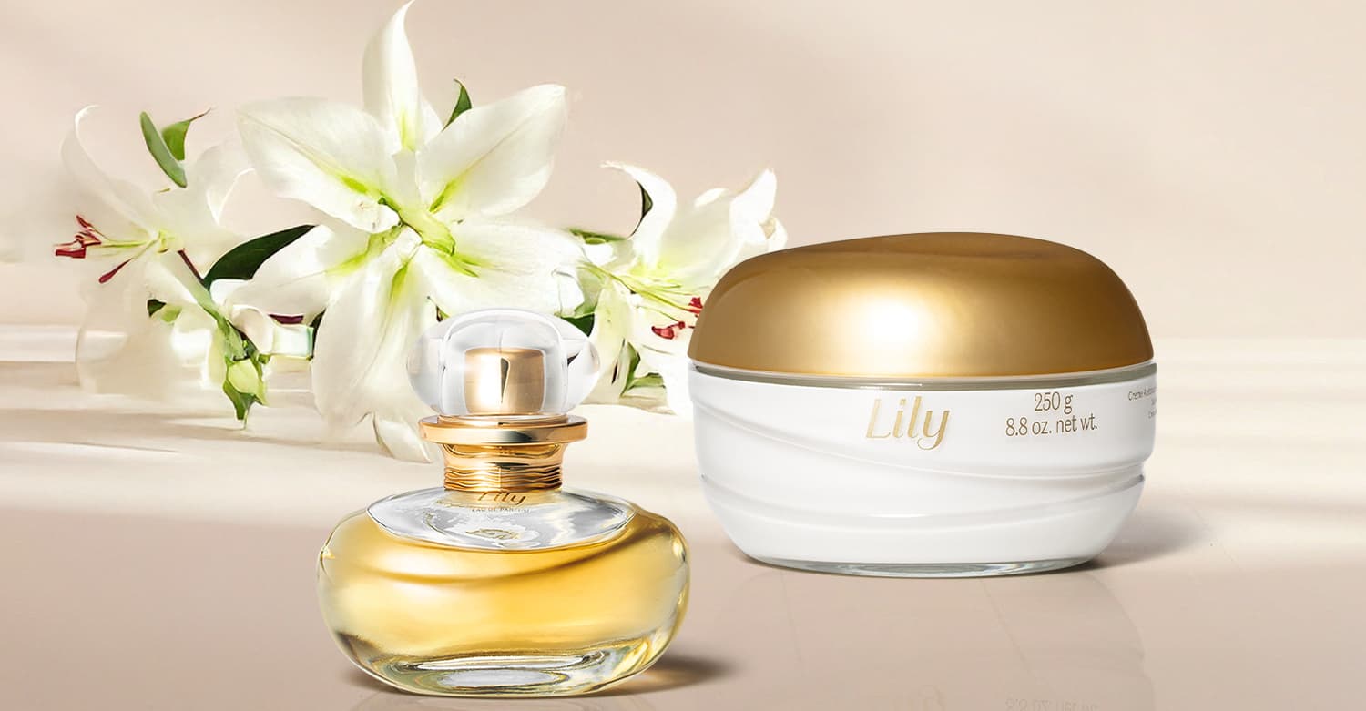 Imagem de um frasco dourado de Eau de Parfum Lily e um pote branco com tampa dourada de creme corporal da mesma marca em fundo e superfície claras e lírios brancos ao lado.