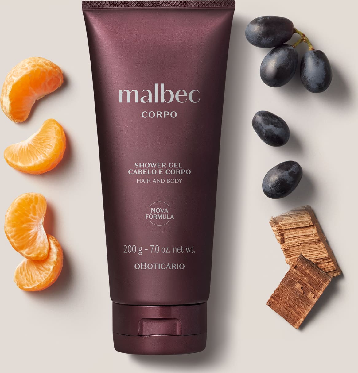 Imagem de um tubo de gel de banho e cabelo da marca Malbec, sobre superfície clara com laranjas e uvas pretas ao redor, em ambiente minimalista e neutro.