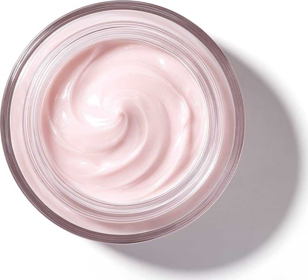 Pote de vidro visto de cima com foco na textura do creme com padrão de espiral suave de textura cremosa e brilhante em tom de rosa claro.