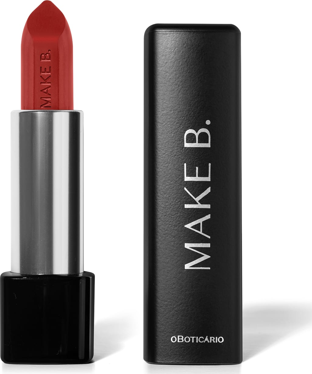 Batom em tom de vermelho alaranjado Make B. aberto. De um lado, a tampa preta com texto em branco, com formato retangular e ponta arredondada. Do outro, a base preta, o corpo prateado e a bala de batom aparente com a marca gravada em baixo relevo.