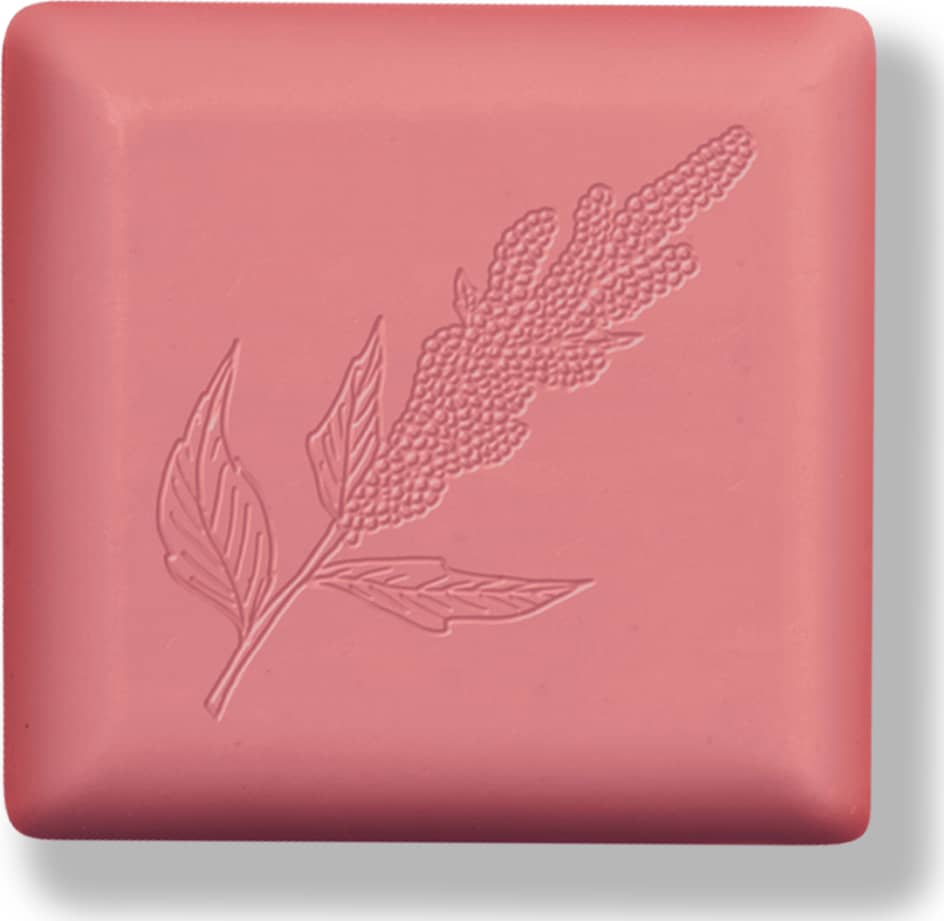 Barra de sabonete quadrada de cor rosa com baixo relevo em formato de folha em tom ligeiramente mais escuro que a barra.