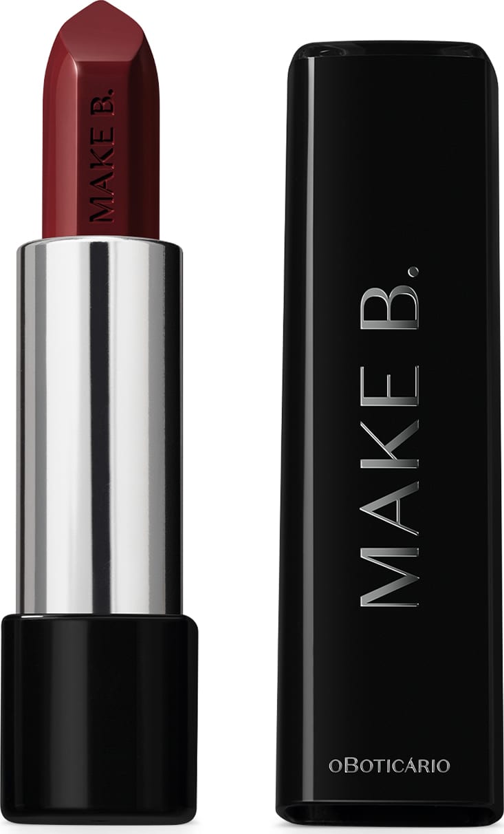 Batom em tom de vermelho escuro da marca Make B. aberto. De um lado, a tampa preta com texto em branco, com formato retangular e ponta arredondada. Do outro, a base preta, o corpo prateado e a bala de batom aparente com a marca gravada em baixo relevo.