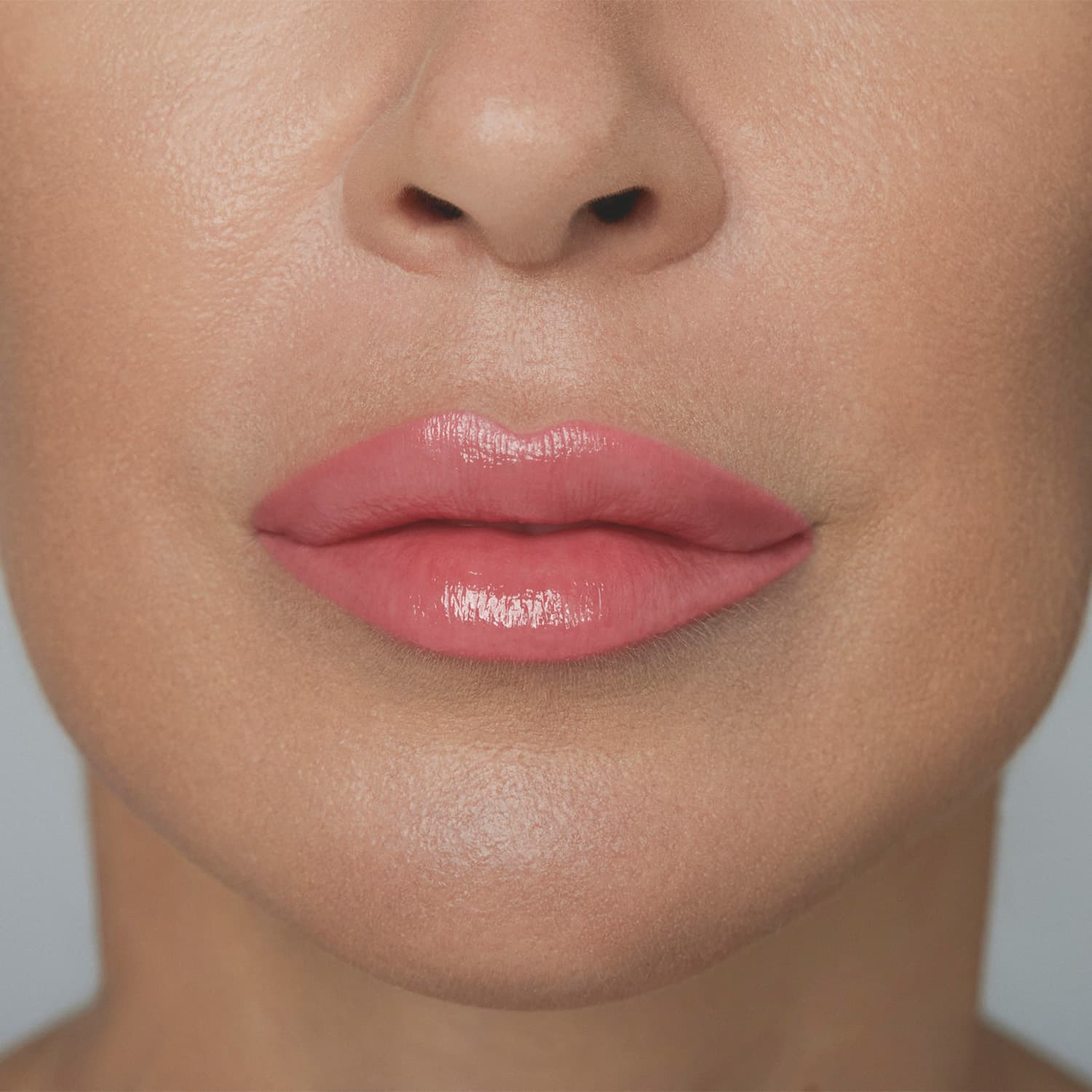 A imagem mostra parte de um rosto feminino em primeiro plano, dando destaque aos lábios, mostrando como o batom rosa da /Make B. fica na pele branca. O fundo é branco e liso.
